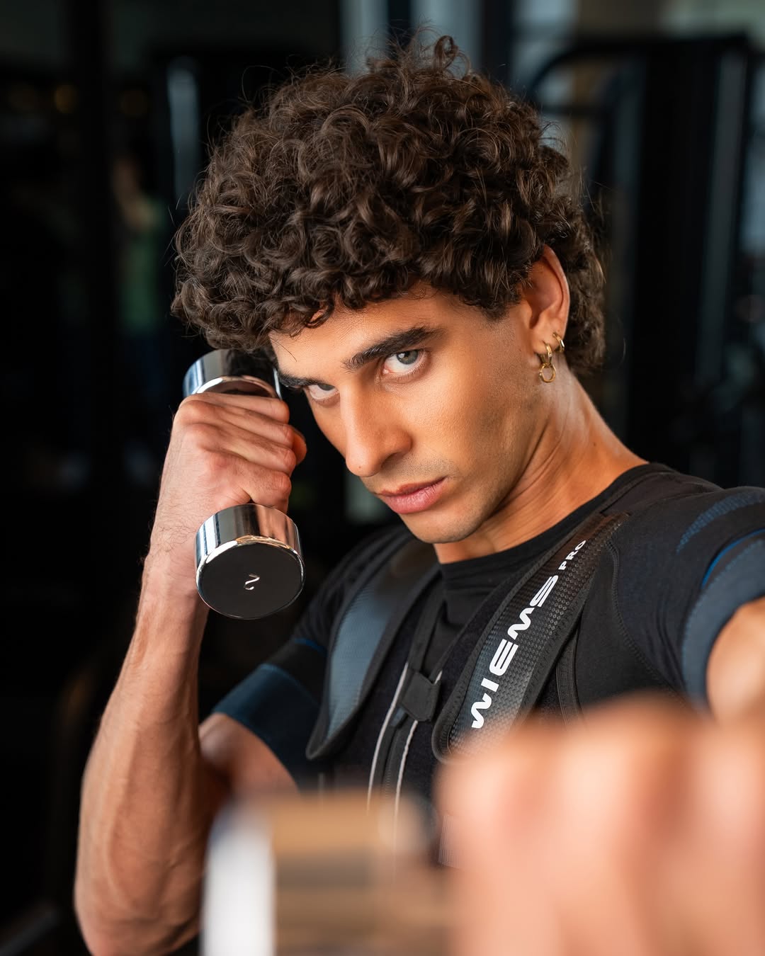 Studio 11 athlete lifting a dumbbell in an EMS suit