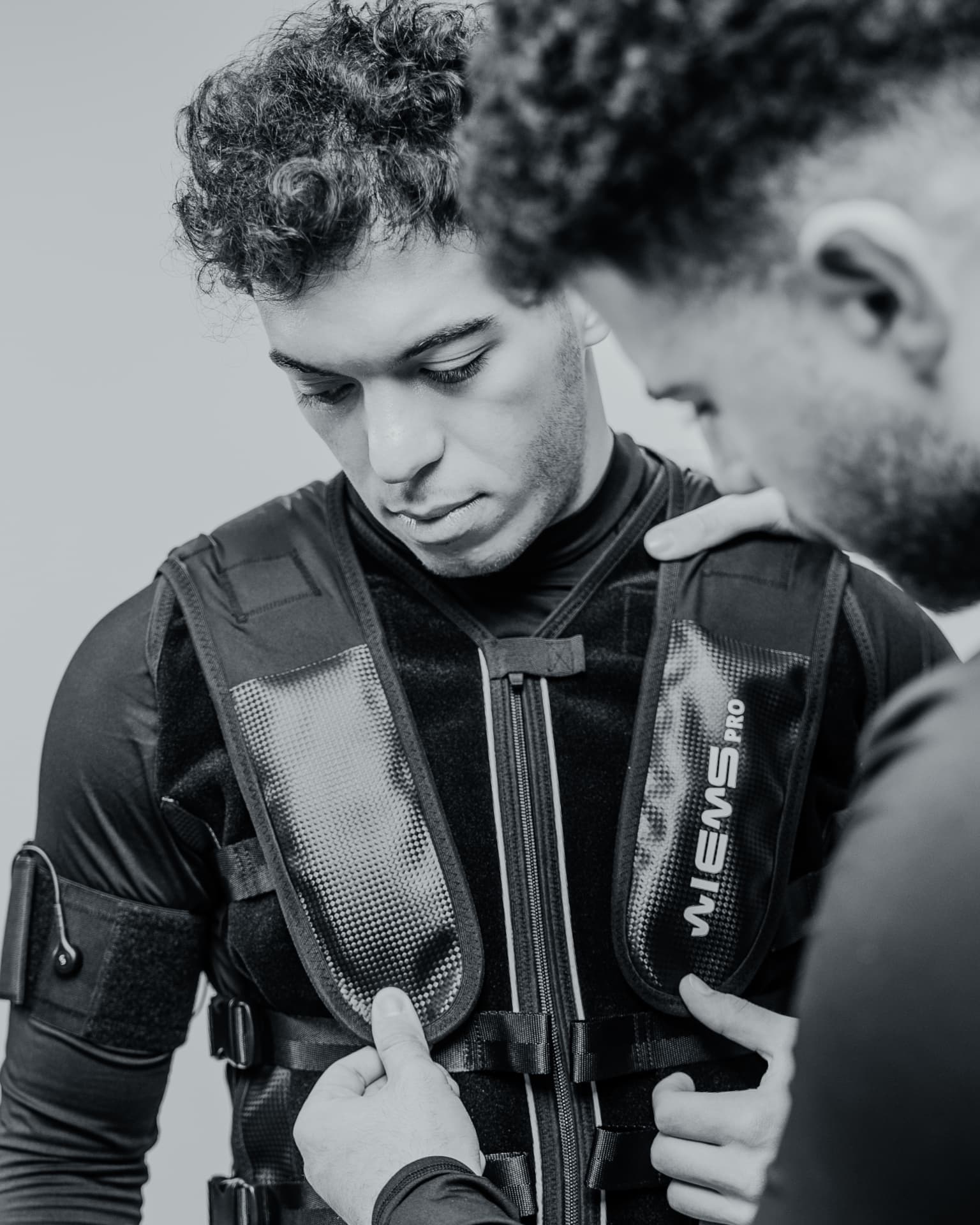Trainer carefully fitting an EMS suit for a client