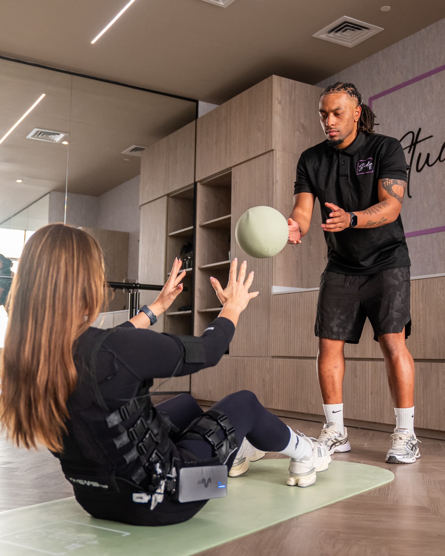 Trainer coaching a client through an active Studio 11 EMS exercise