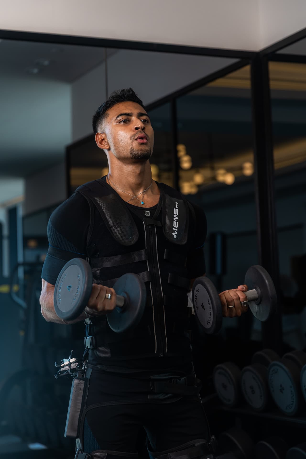 Studio 11 athlete performing dumbbell curls in an EMS suit