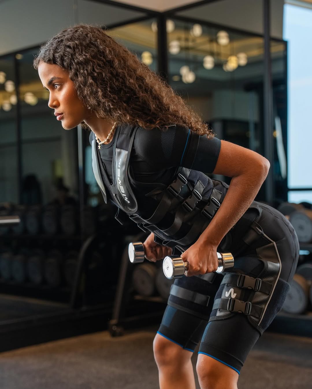 Woman training with dumbbells in an EMS suit